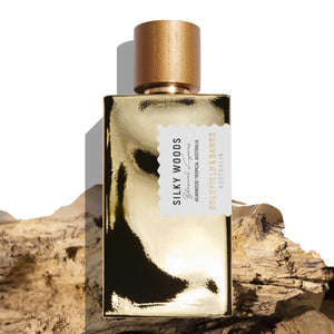 Goldfield & Banks - Botanical Series - Silky Woods Parfumflakon in glänzendem goldfarbenem Design mit braunem Holzverschluss auf Holzstücken