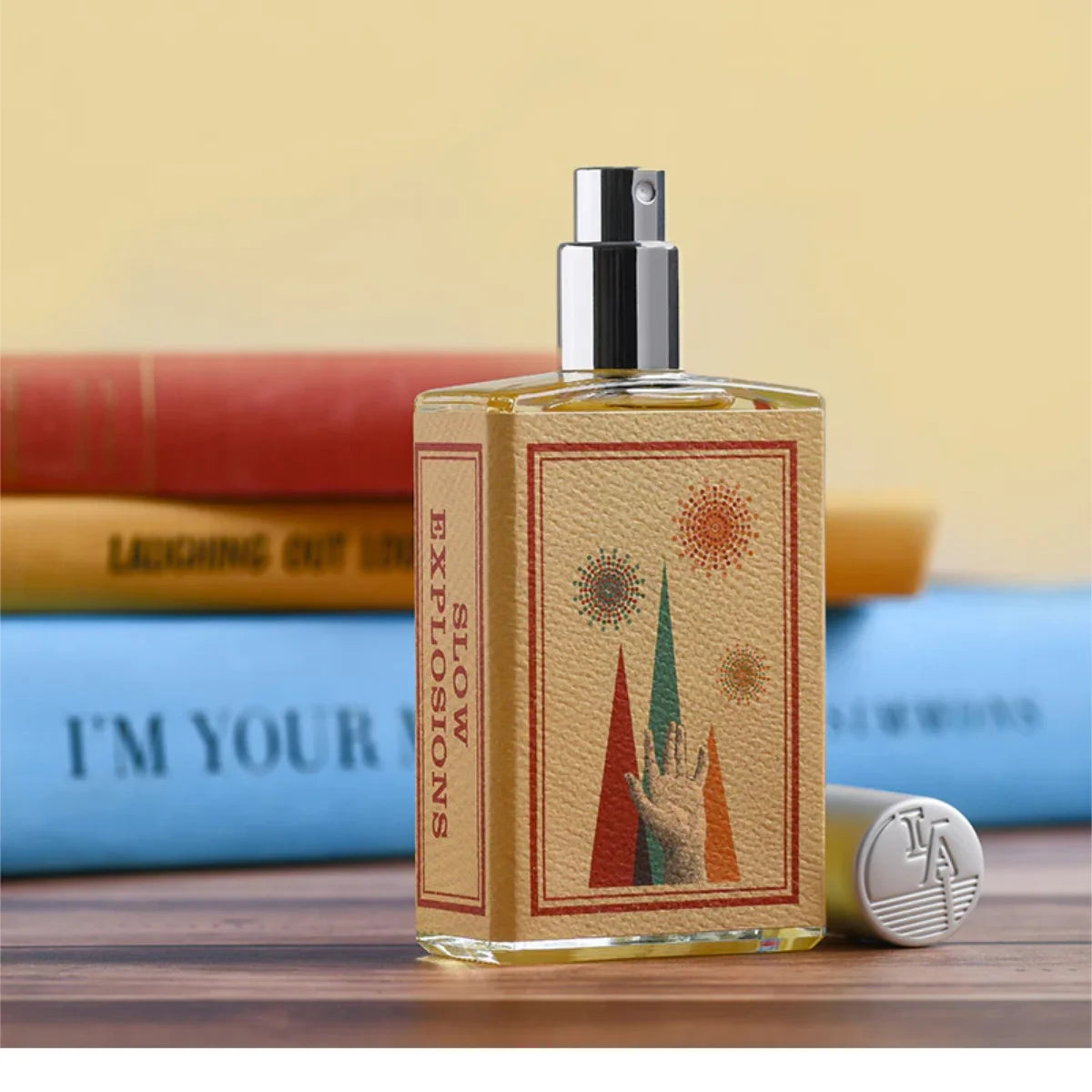 Imaginary Authors - Slow Explosions Parfumspray mit kreativem Etikett und silbernem Zerstäuber vor bunten Büchern
