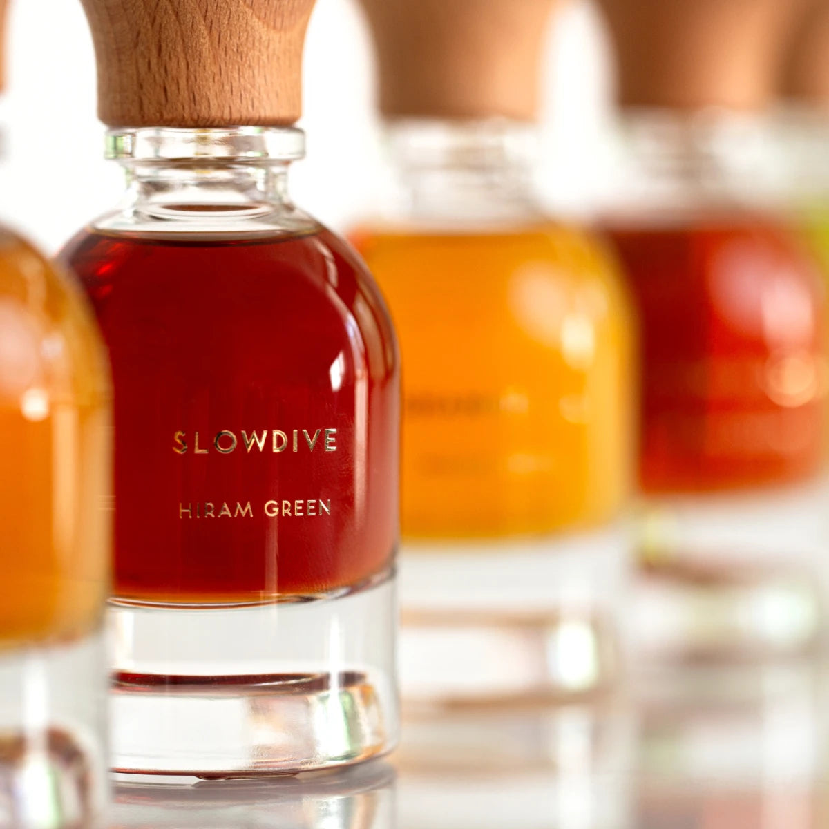 Hiram Green - Slowdive flasche mit tief bernsteinfarbenem duft und hellem holzverschluss vor unscharfem hintergrund