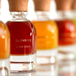 Hiram Green - Slowdive flasche mit tief bernsteinfarbenem duft und hellem holzverschluss vor unscharfem hintergrund