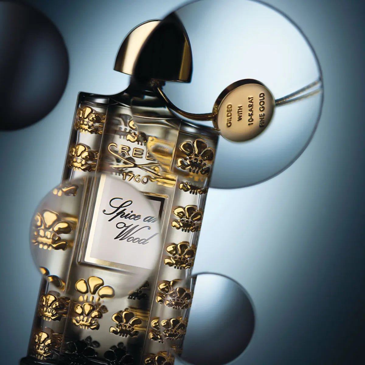 Creed - Les Royales Exclusives - Spice and Wood Flakon mit goldenen Ornamenten und elegantem Verschluss vor blauem Hintergrund