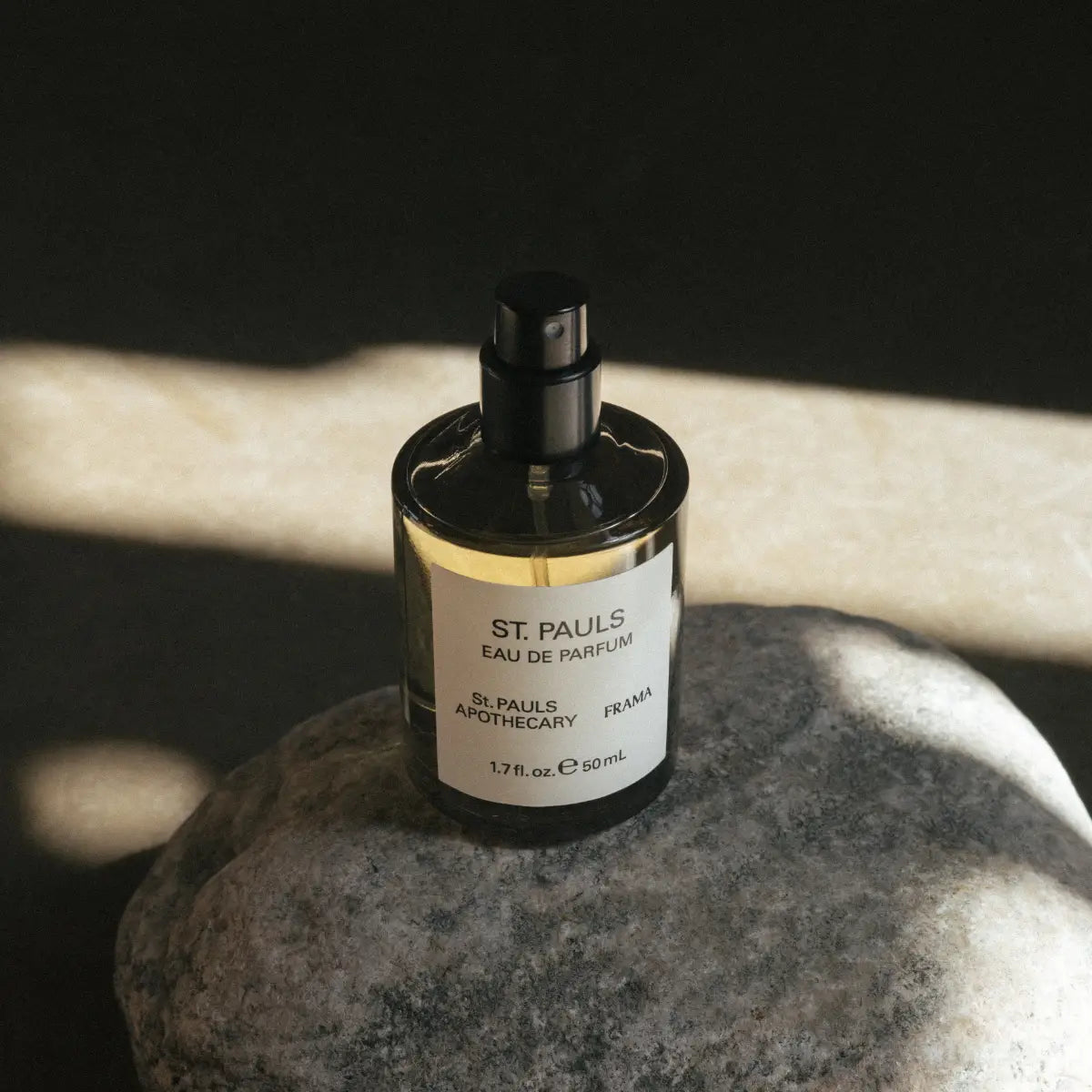 FRAMA - St. Pauls Eau de Parfum Flakon mit schwarzem Spraykopf auf grauem Stein und Schattenwurf
