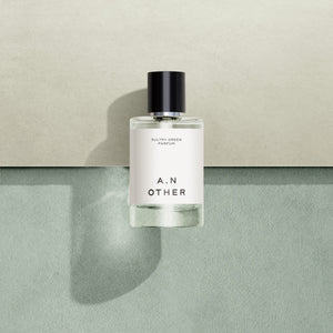 A.N. OTHER - Sultry Green Parfumflakon mit schlichtem Etikett und schwarzem Verschluss vor zweifarbigem Hintergrund