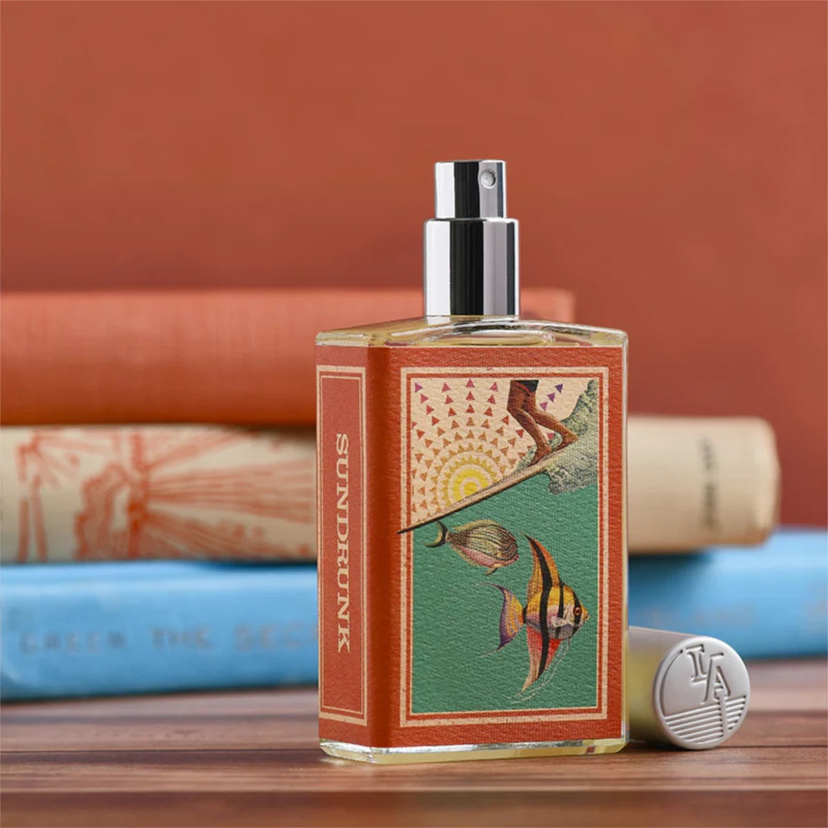 Imaginary Authors - Sundrunk Parfumflakon mit sommerlichem, farbenfrohem Etikett und silbernem Sprühkopf auf Holzuntergrund