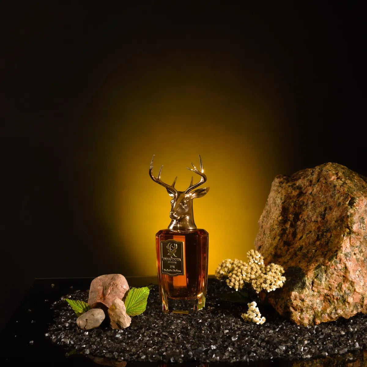 Pana Dora Sweden - XVI Parfumflakon mit goldenem Hirschkopf vor dunklem Hintergrund und dekorativen Steinen