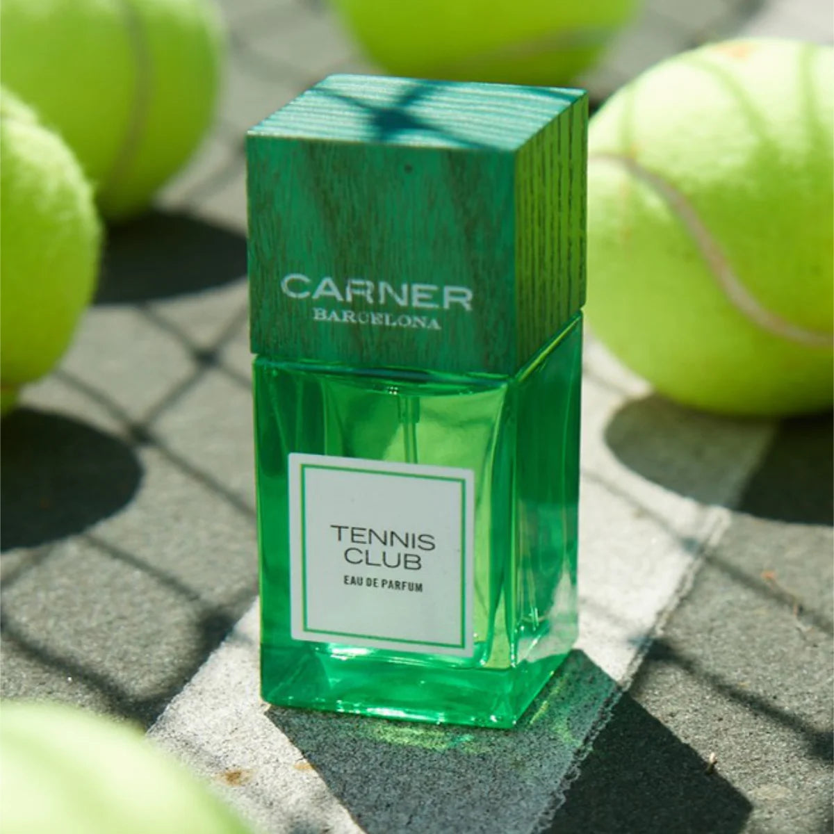 Carner Barcelona - Summer Journey Collection - Tennis Club Parfumflakon in grünem Glas mit Holzdeckel auf Tennisplatz mit Bällen