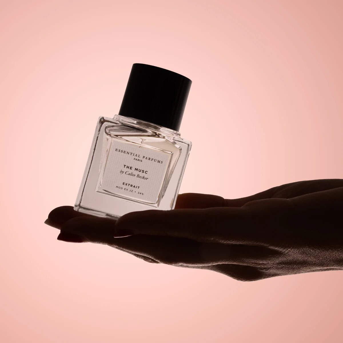 Essential Parfums - The Musc - Extrait de Parfum zeigt klaren Flakon auf geöffneter Hand vor warmem Hintergrund