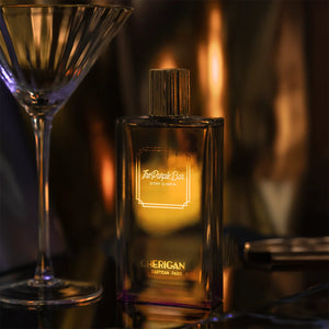 Cherigan - The Purple Bar edler Parfumflakon mit goldfarbenem Verschluss vor warmem, stimmungsvollem Hintergrund