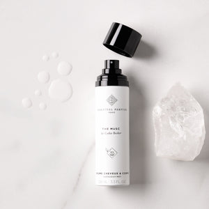 Essential Parfums - The Musc - Hair & Body Mist Sprayflasche mit offenem schwarzen Deckel und Kristall auf hellem Untergrund
