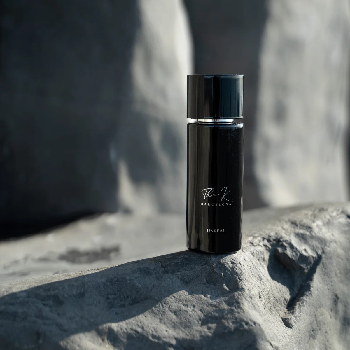 Kinetic Perfumes - Unreal eleganter schwarzer Parfumflakon mit schlichtem Design auf rauem Stein unter natürlichem Licht