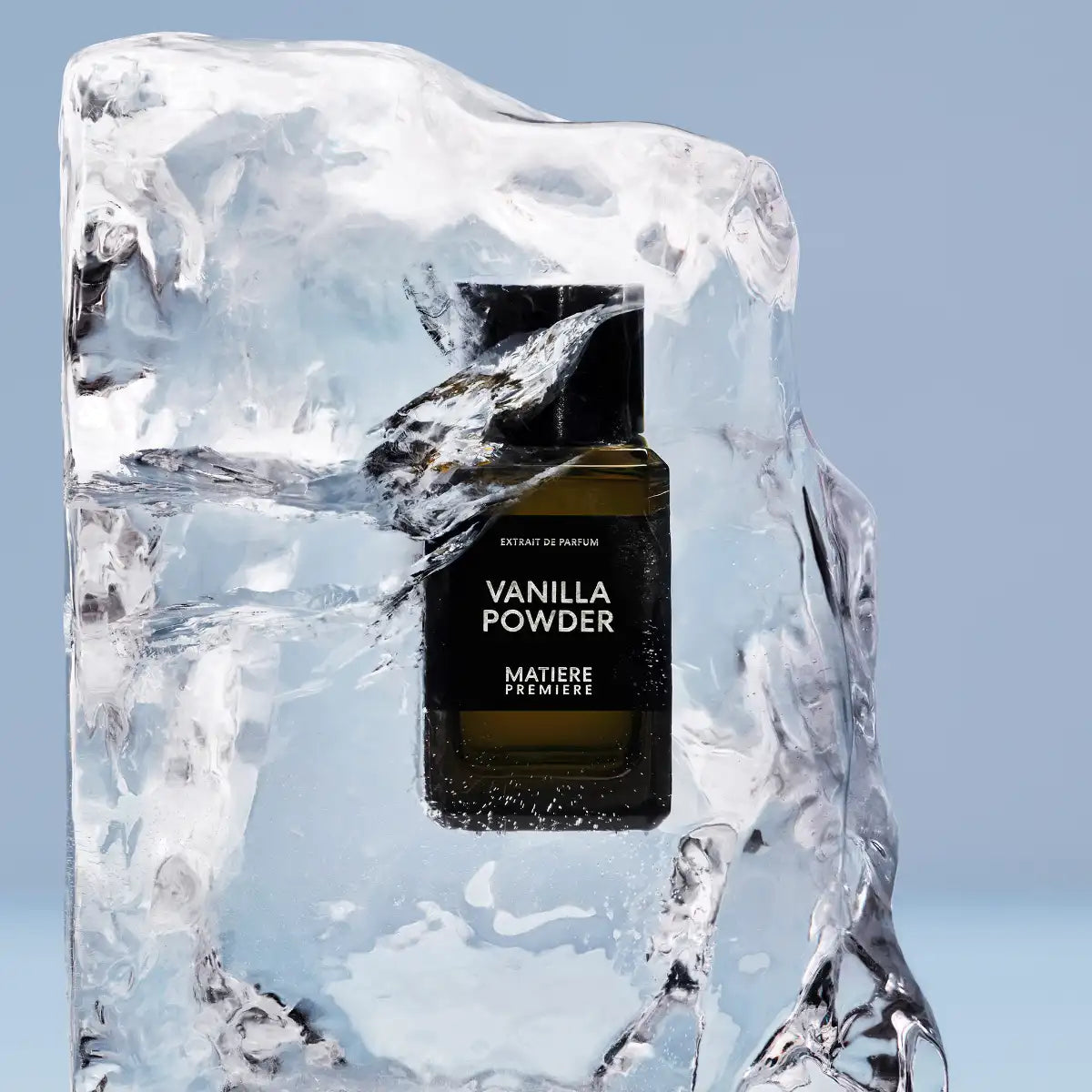 Matière Première - Vanilla Powder - Extrait Parfumflakon elegant in Eisblock eingefroren vor hellblauem Hintergrund