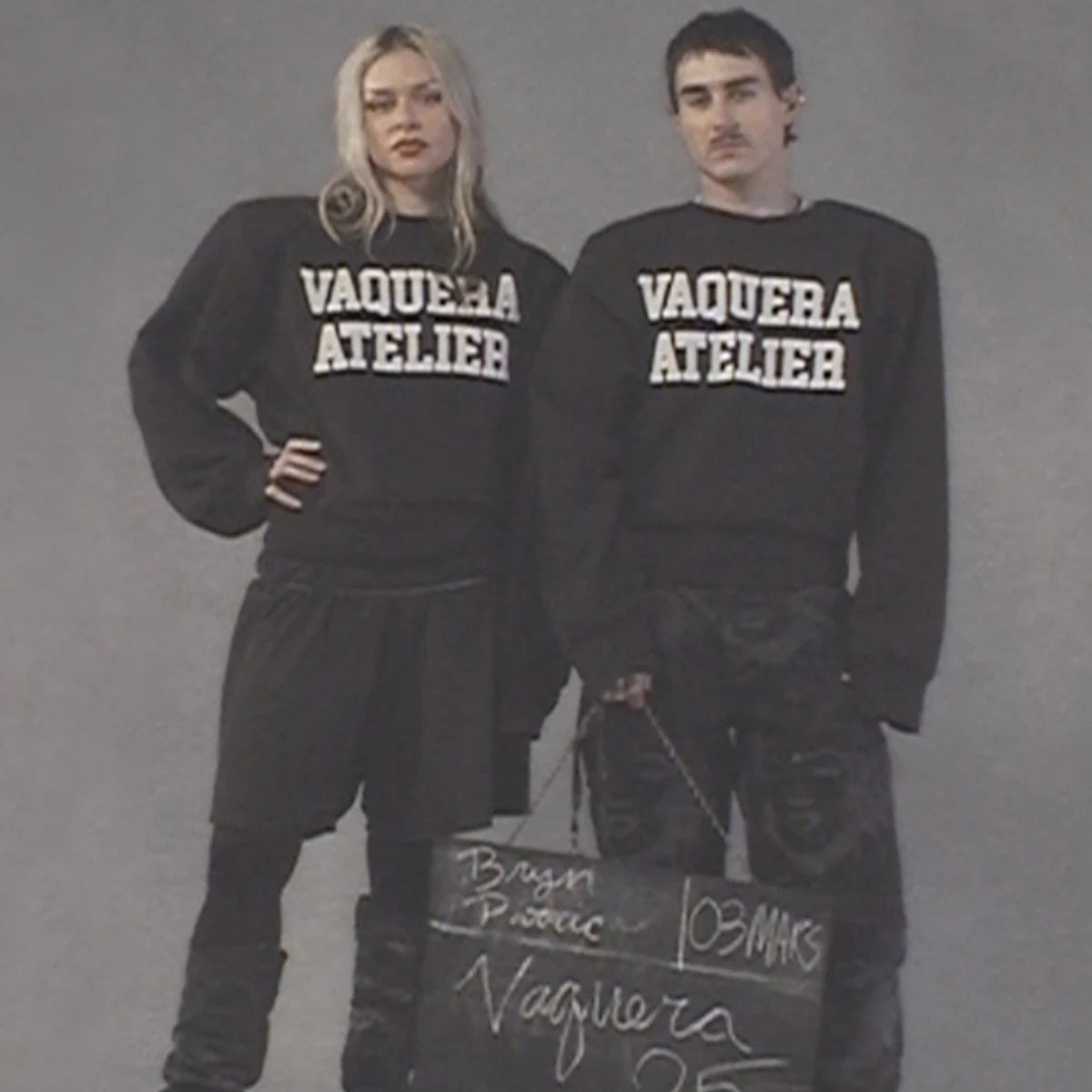 Comme des Garçons - Vaquera Classique Perdu zeigt zwei Models mit schwarzen VAQUERA ATELIER Sweatshirts vor neutralem Hintergrund