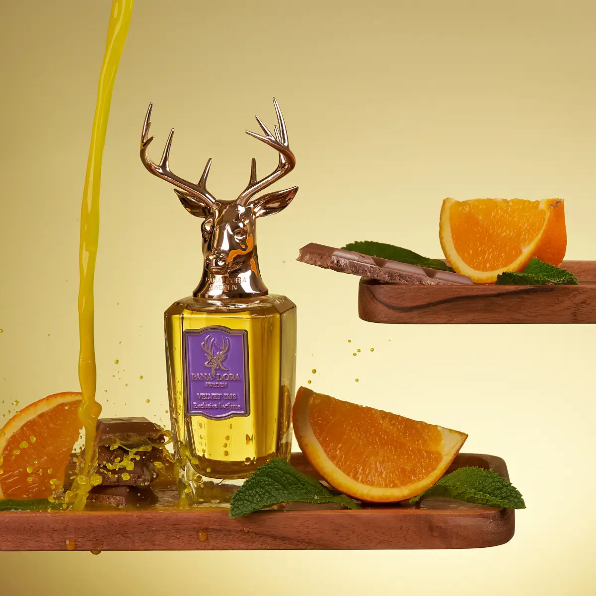 Pana Dora Sweden - Velvet Iris Parfumflakon mit Hirschkopfverschluss umgeben von Orangen und Minzblättern vor gelbem Hintergrund