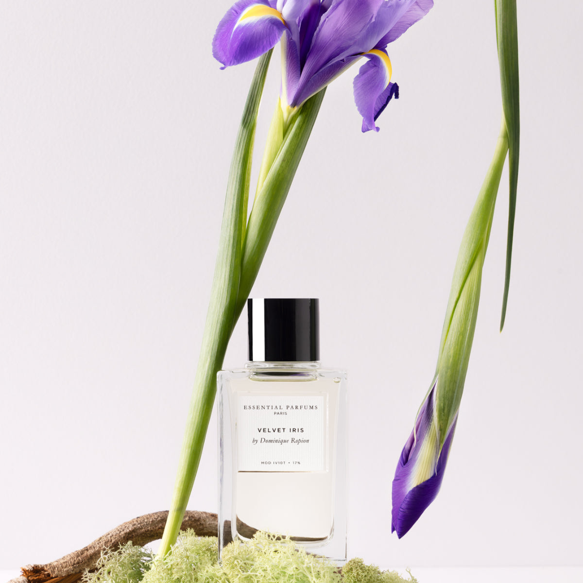 Essential Parfums - Velvet Iris Flakon mit schwarzem Verschluss und lila Irisblüten auf hellem Hintergrund