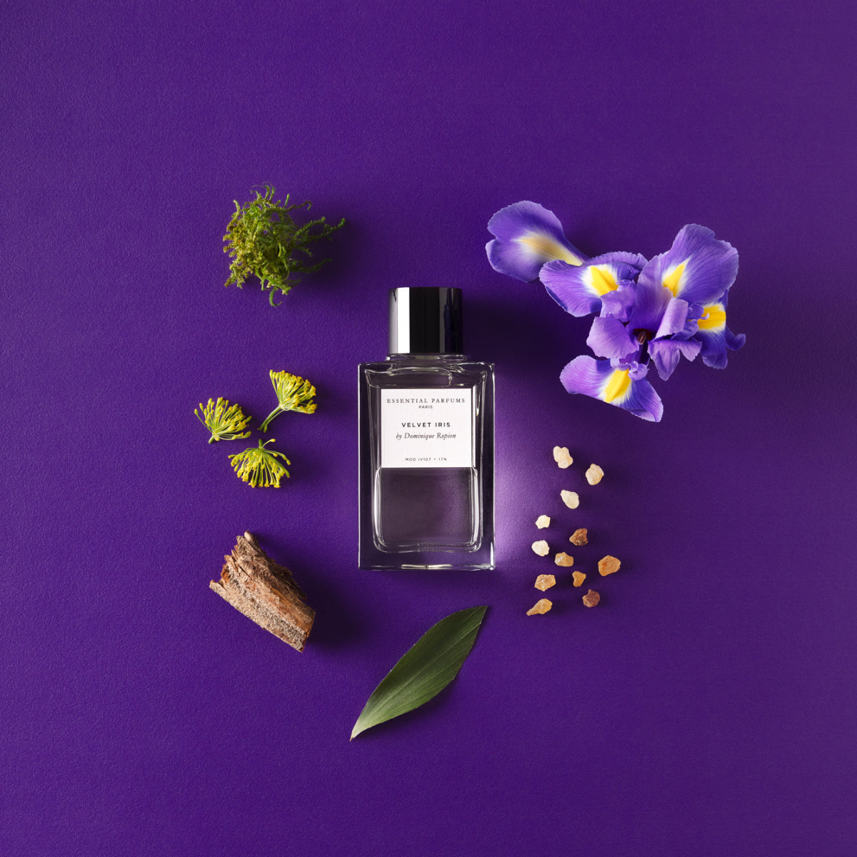 Essential Parfums - Velvet Iris Parfumflakon mit schwarzen Verschluss und natürlichen Bestandteilen auf lila Hintergrund
