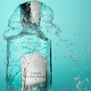 Creed - Virgin Island Water klarer Flakon mit silbernem Verschluss umgeben von spritzendem Wasser vor türkisfarbenem Hintergrund