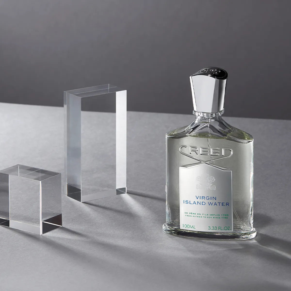 Creed - Virgin Island Water klarer Flakon mit silbernem Verschluss vor grauem Hintergrund und kristallklaren Blöcken