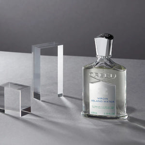 Creed - Virgin Island Water klarer Flakon mit silbernem Verschluss vor grauem Hintergrund und kristallklaren Blöcken