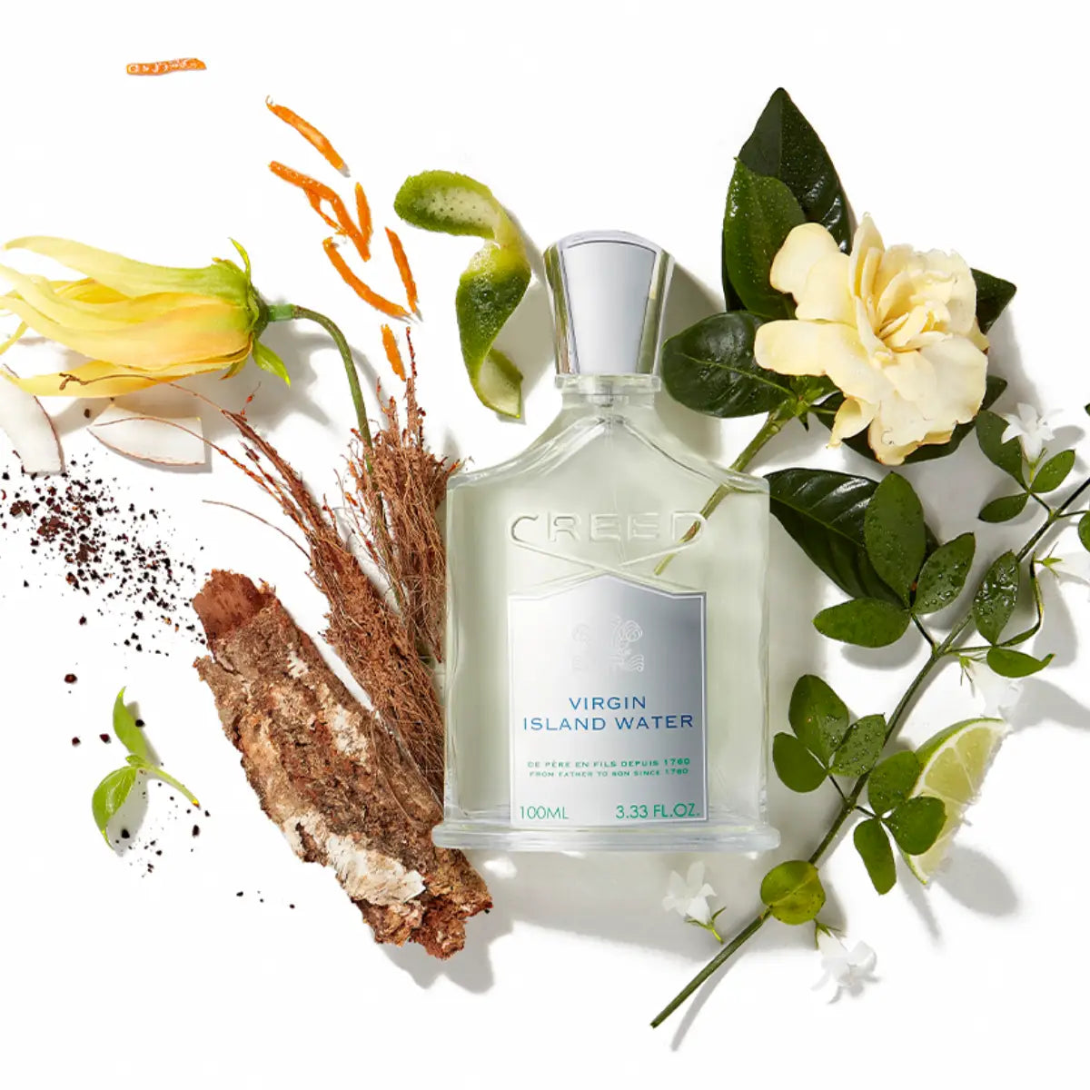 Creed - Virgin Island Water Flakon mit silbernem Verschluss umgeben von Blüten und Pflanzen auf weißem Hintergrund