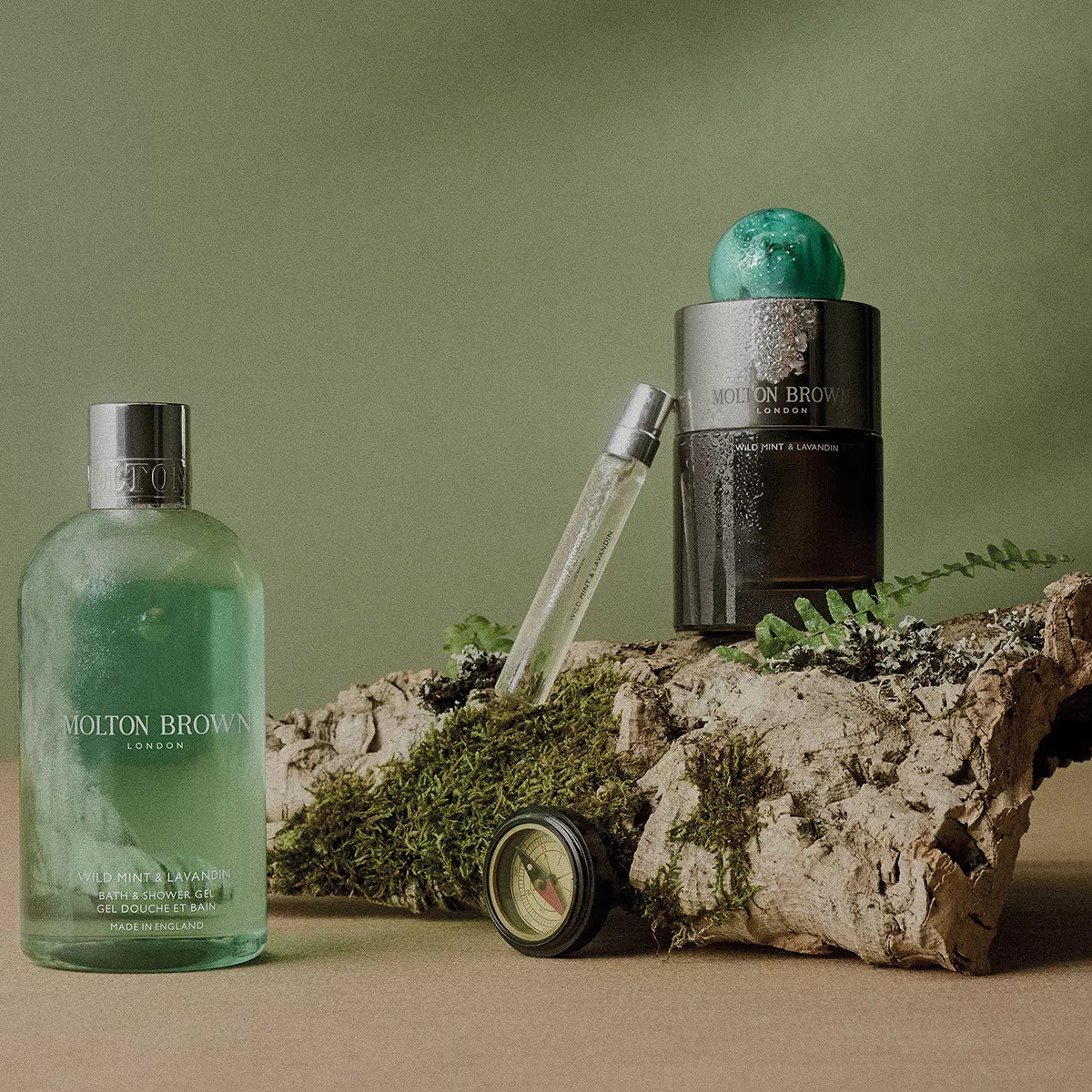 Molton Brown - Wild Mint & Lavandin - Eau de Parfum mit grünem Flakon und passendem Duschgel auf Naturholz inszeniert