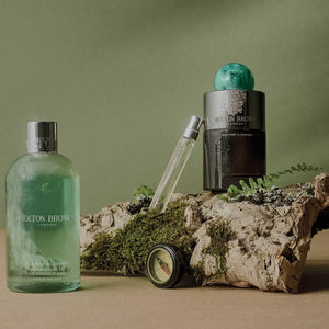 Molton Brown - Wild Mint & Lavandin - Eau de Parfum mit grünem Flakon und passendem Duschgel auf Naturholz inszeniert