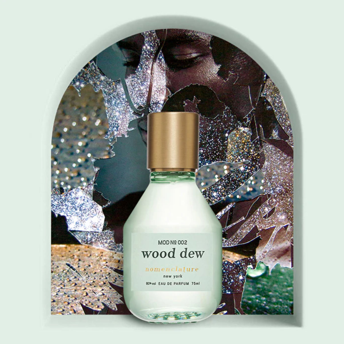 Nomenclature - wood dew Parfumflakon mit milchigem Glas und goldfarbenem Verschluss vor künstlerischem Hintergrund