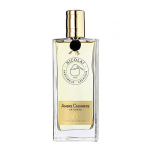 Nicolaï - Ambre Cashmere Intense Parfumflakon mit goldfarbenem Verschluss und bernsteinfarbener Flüssigkeit vor weißem Hintergrund