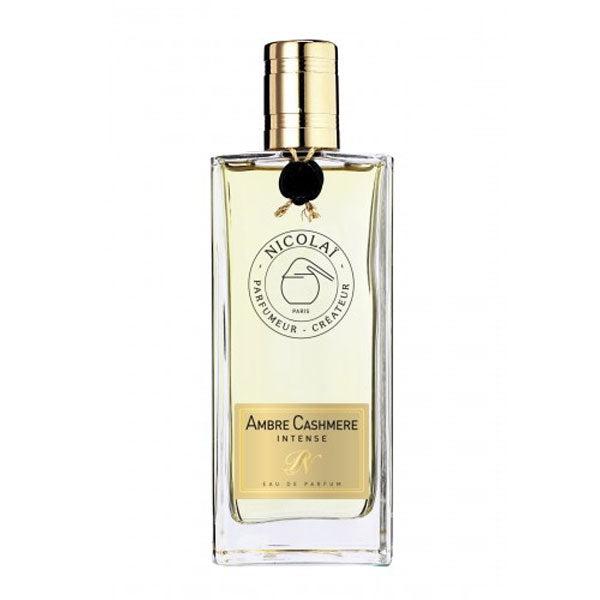 Nicolaï - Ambre Cashmere Intense Parfumflakon mit goldfarbenem Verschluss und bernsteinfarbener Flüssigkeit vor weißem Hintergrund
