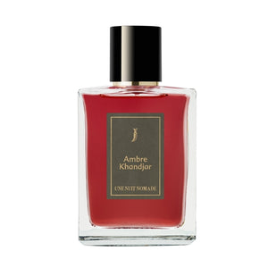 Une Nuit Nomade - Une Nuit a Oman - Ambre Khandjar Parfumflakon mit tiefrotem Inhalt und schwarzer Kappe vor weißem Hintergrund