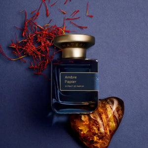 Atelier Materi - Ambre Papier Parfumflakon in tiefblauem Glas mit goldfarbenem Deckel auf dunkelblauem Untergrund