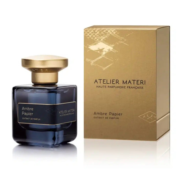 Atelier Materi - Ambre Papier Parfumflakon in dunklem Glas mit goldfarbenem Deckel neben goldfarbener Verpackung