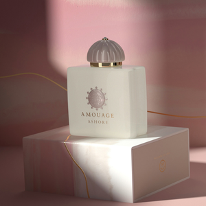 Amouage - Renaissance Collection - Ashore eleganter cremig-weißer Flakon mit geometrischem Verschluss vor rosa Hintergrund