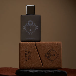 Spiritum - 2 - Astral Twin Parfumflakon in dunklem Design mit geometrischem Symbol und brauner Box auf braunem Hintergrund
