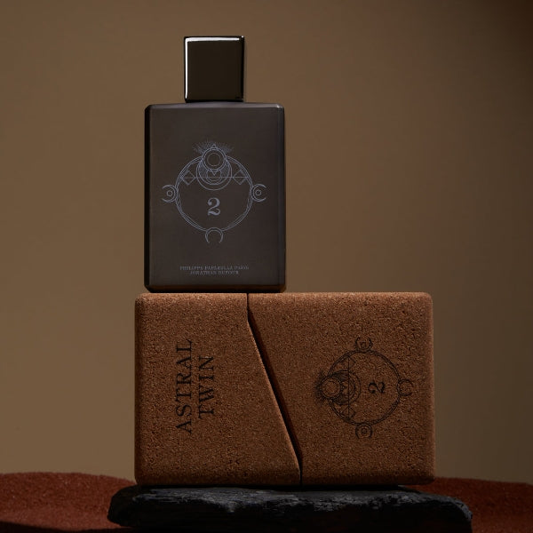 Spiritum - 2 - Astral Twin Parfumflakon in dunklem Design mit geometrischem Symbol und brauner Box auf braunem Hintergrund
