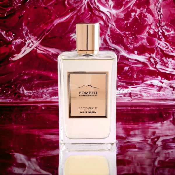 Pompeii - Baccanale Parfumflakon mit klarem Glas und roségoldenem Etikett vor fließendem rotem Hintergrund