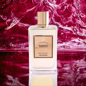 Pompeii - Baccanale Parfumflakon mit klarem Glas und roségoldenem Etikett vor fließendem rotem Hintergrund