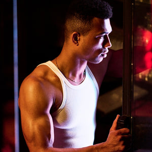 HUNQ - #002 Barman zeigt muskulösen Mann im weißen Tanktop mit konzentriertem Blick in warmem Lichtspiel