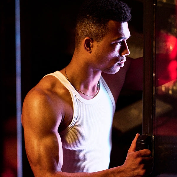 HUNQ - #002 Barman zeigt muskulösen Mann im weißen Tanktop mit konzentriertem Blick in warmem Lichtspiel