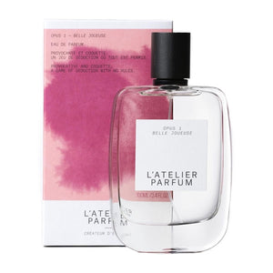 L'Atelier Parfum - Opus 1 - Belle Joueuse klarer Flakon mit schwarzem Verschluss und pinkfarbenem Karton im Hintergrund