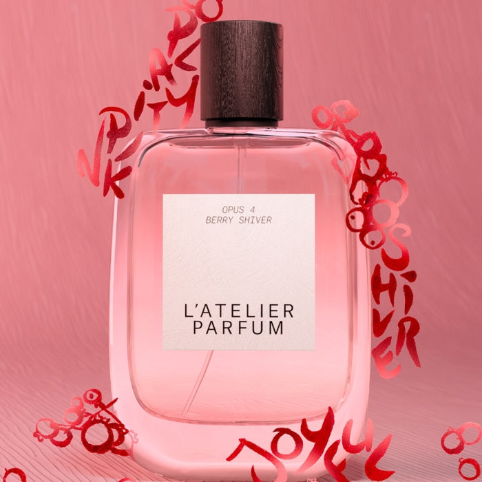 L'Atelier Parfum - Opus 4 - Berry Shiver Flakon mit braunem Holzverschluss vor rosa Hintergrund mit roten Schriftzeichen
