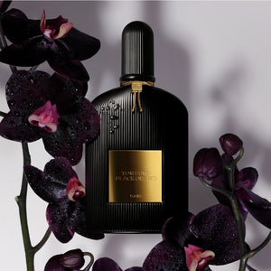 Tom Ford - Signature - Black Orchid - Eau de Parfum edler schwarzer Flakon mit geriffeltem Design und goldenem Emblem umgeben von dunklen Orchideen