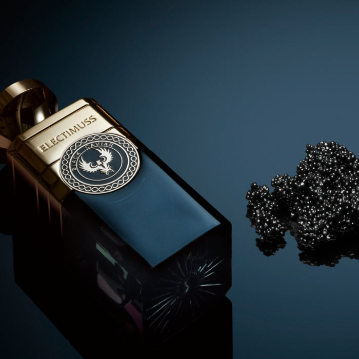 Electimuss - Black Caviar Flakon mit goldenem Verschluss und tiefblauem Glas vor schwarzem Kaviar auf dunklem Hintergrund