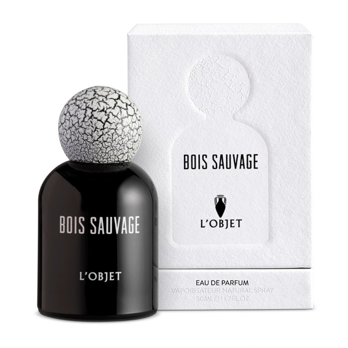 L'Objet - Bois Sauvage Parfumflakon in schwarzem Glas mit weiß-rissigem Kugelverschluss vor weißer Verpackung