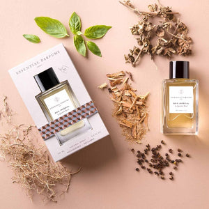 Essential Parfums - Bois Impérial Flakon mit Verpackung umgeben von Kräutern und Holzstücken auf hellem Untergrund