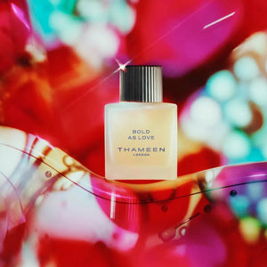 Thameen - Britologne Collection - Bold as Love Flakon mit mattem Glas und schwarzem geriffeltem Verschluss vor farbenfrohem Hintergrund