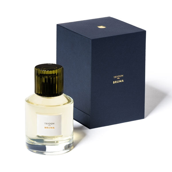 Trudon - Bruma Parfumflakon mit olivgrün geriffeltem Verschluss und heller Flüssigkeit neben dunkelblauer Verpackung