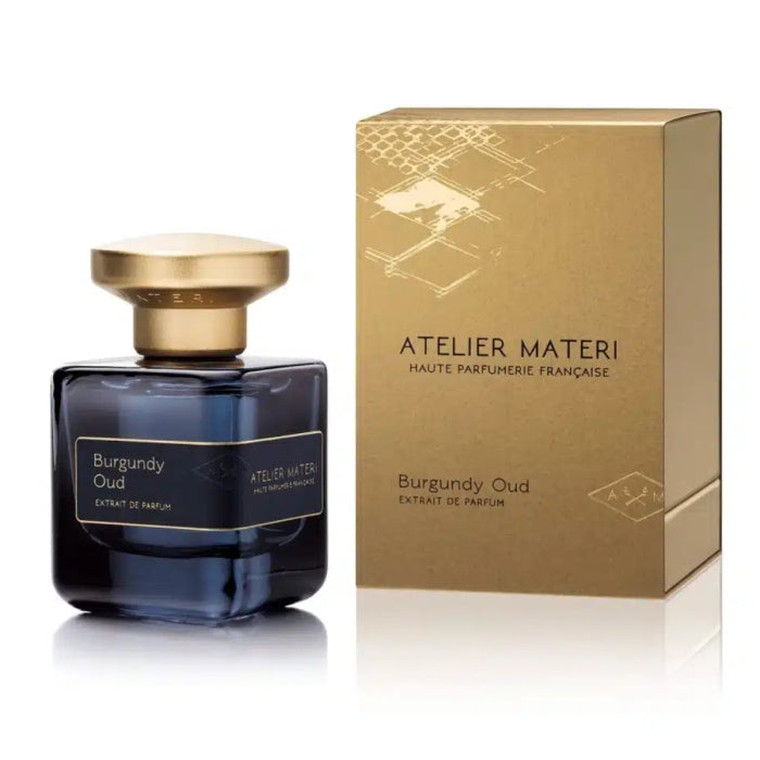 Atelier Materi - Burgundy Oud Parfumflakon in dunklem Glas mit goldenem Deckel neben goldfarbener Verpackung