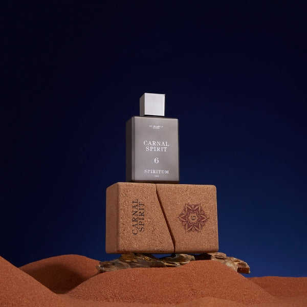 Spiritum - 6 - Carnal Spirit Parfumflakon in dunklem Design auf braunem Korkblock vor tiefblauem Hintergrund