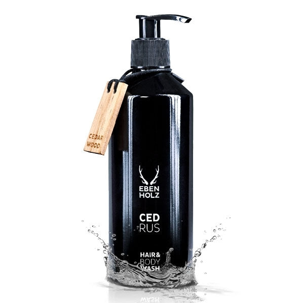 EBENHOLZ - Cedrus Hair & Body Wash schwarze Flasche mit Pumpspender und Holzanstecker vor weißem Hintergrund mit Wasserplash