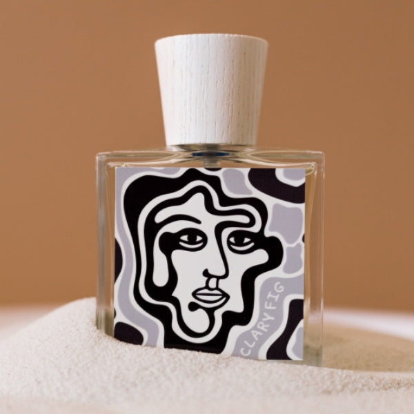 Carl Kling Parfums - Clary Fig mit modernem Flakon und stilisiertem Gesichtsmotiv vor warmem sandfarbenem Hintergrund
